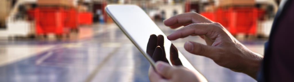 Person using a tablet with a warehouse in the background