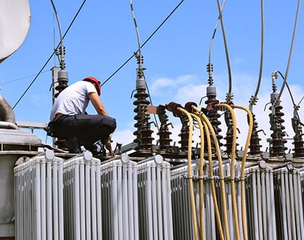 Electrician working on high voltage transformer in power station