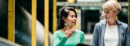 Two women walking and talking about work