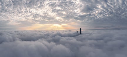 A stone tower protruding between levels of clouds