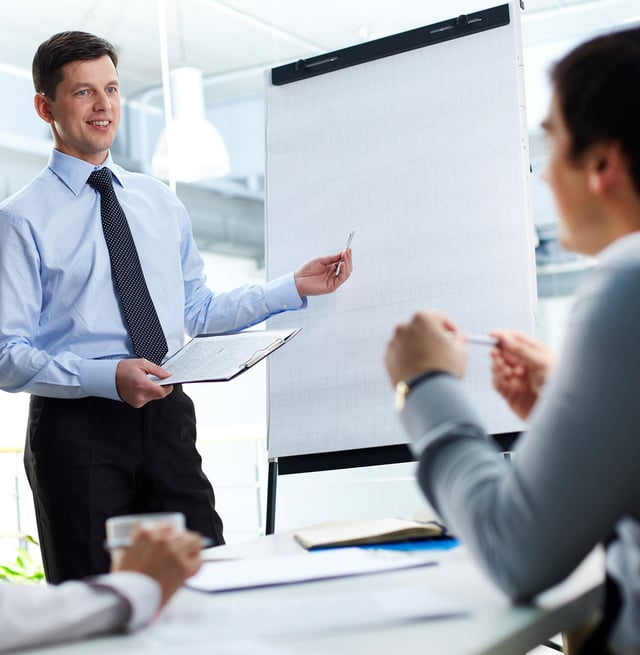 Two people listening to trainer by a flipchart.