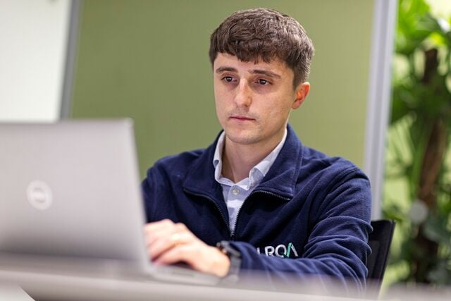 Profissional da LRQA trabalhando em laptop em ambiente corporativo