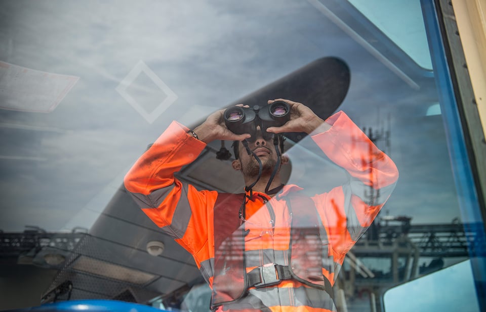 Man with binoculars looking through window